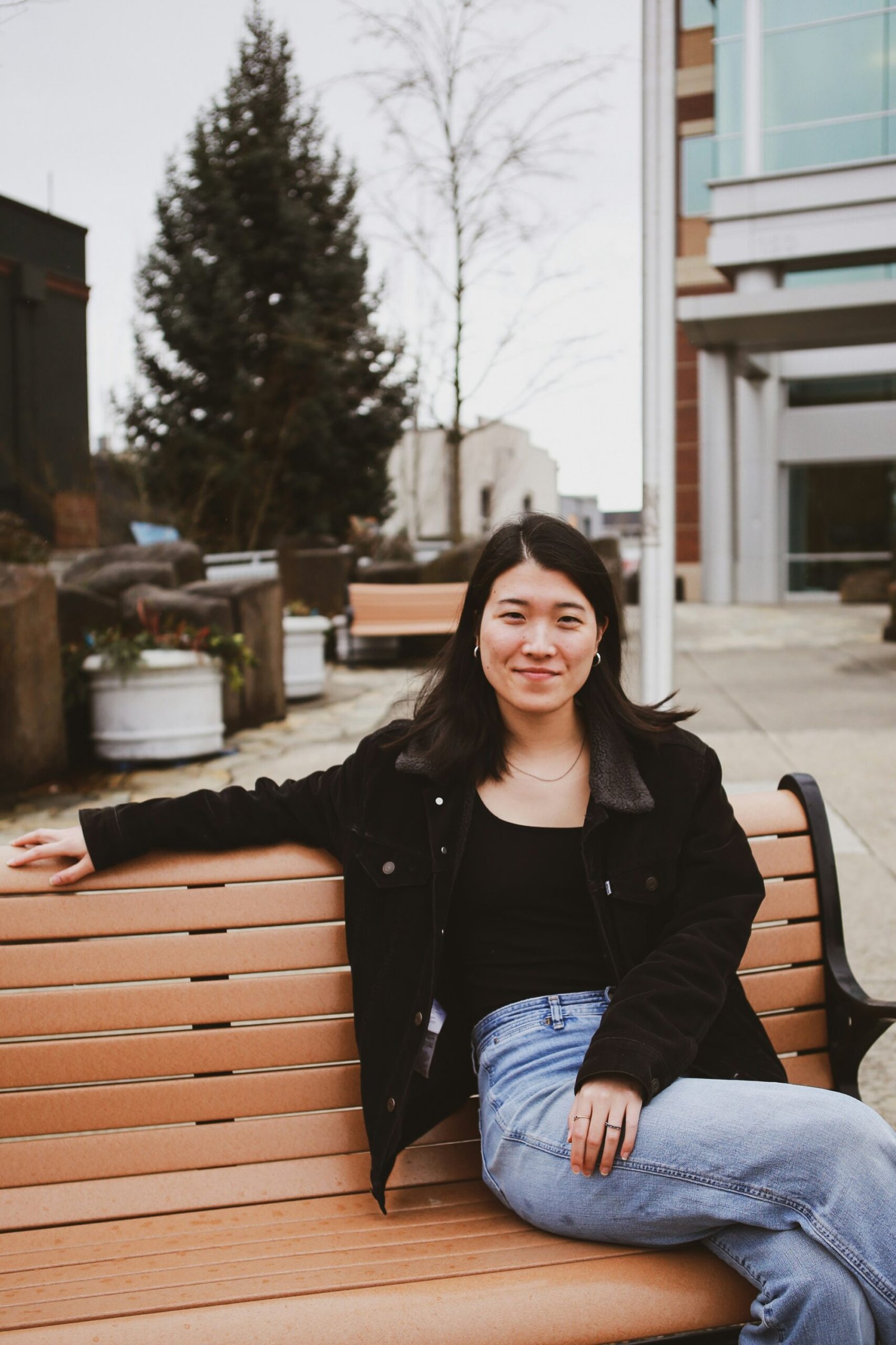 a woman sitting on top of a wooden bench